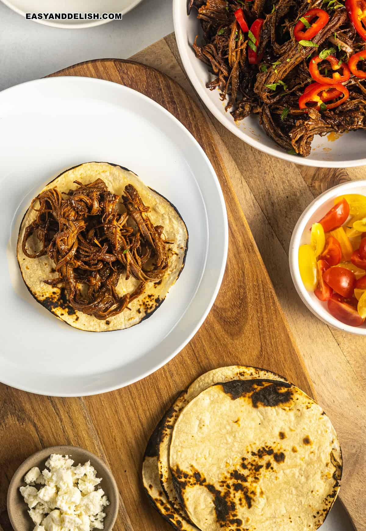 pulled beef over corn tortillas and garnishes around it. 