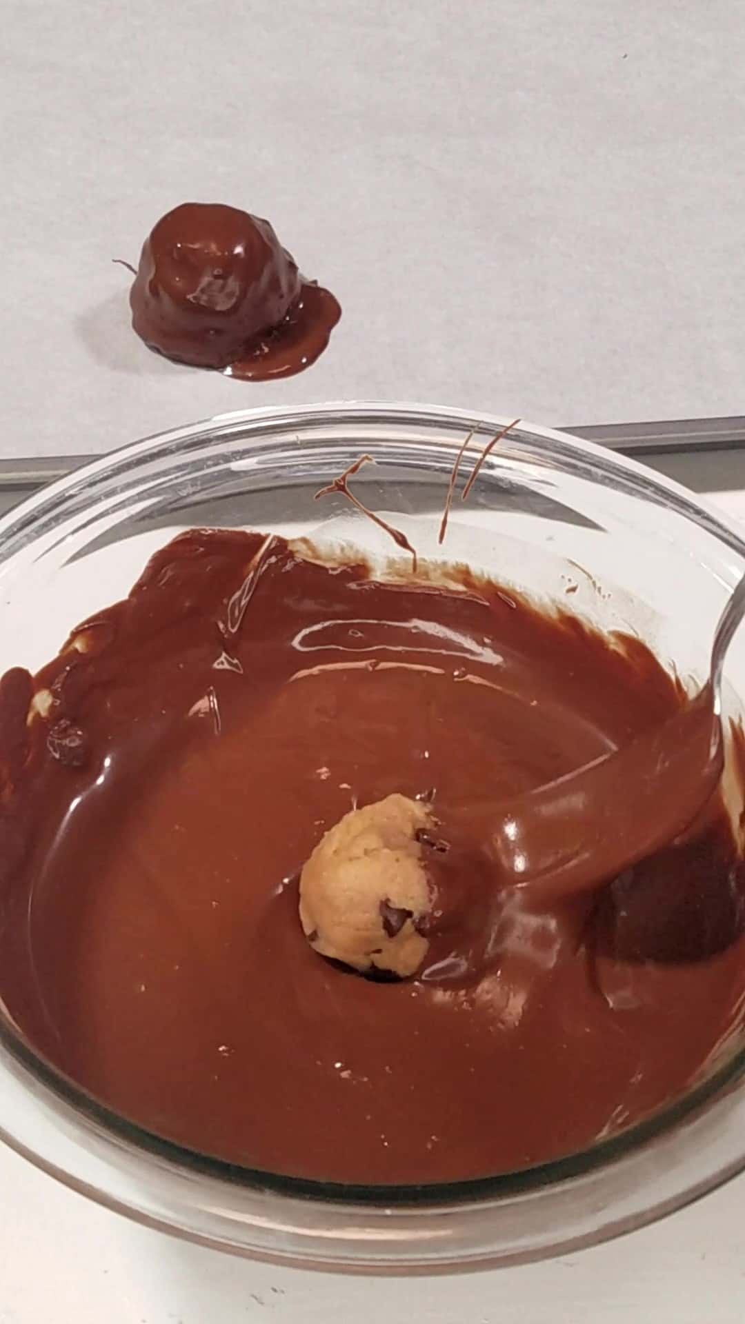 Dipping protein balls in melted chocolate.