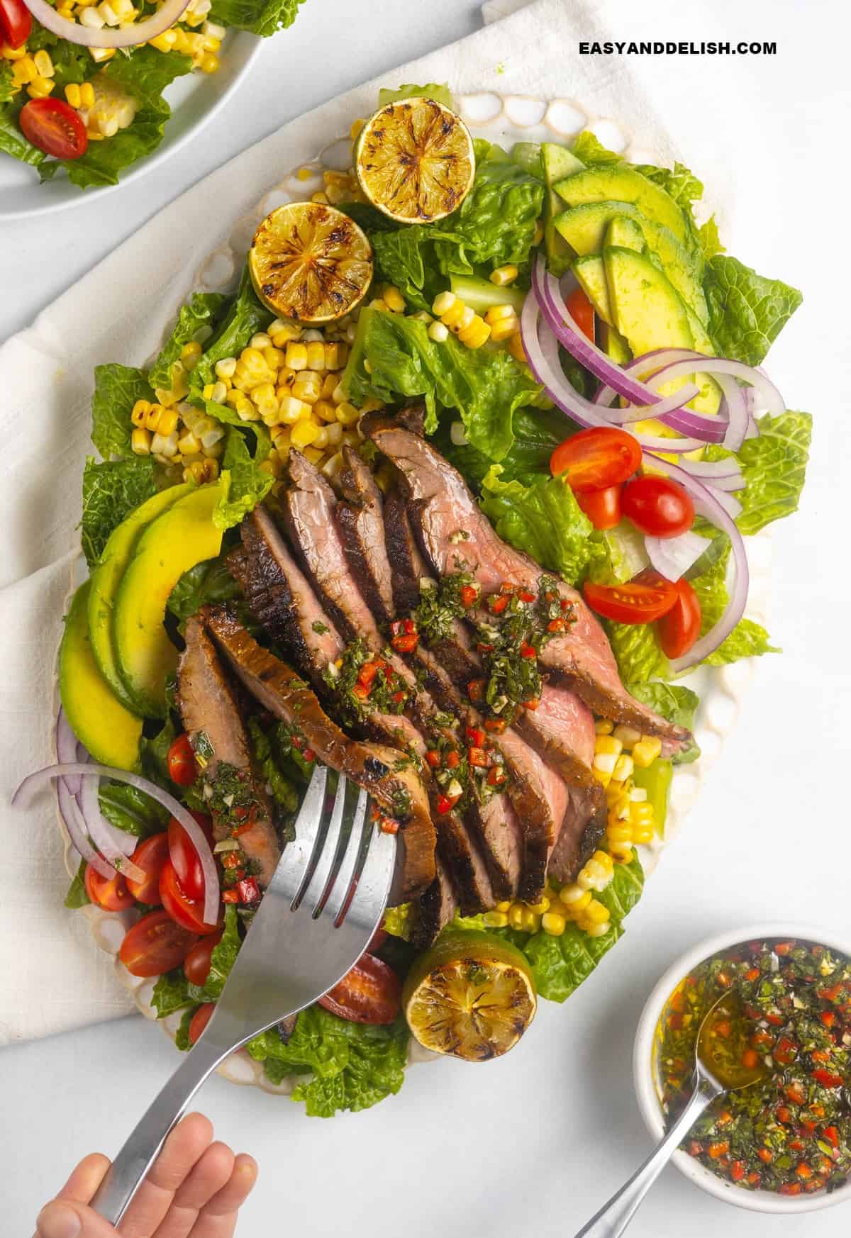 a fork holding a piece of steak salad.