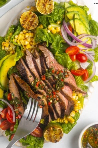 A forkful of flank steak salad taken from a platter.