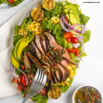 A forkful of flank steak salad taken from a platter.