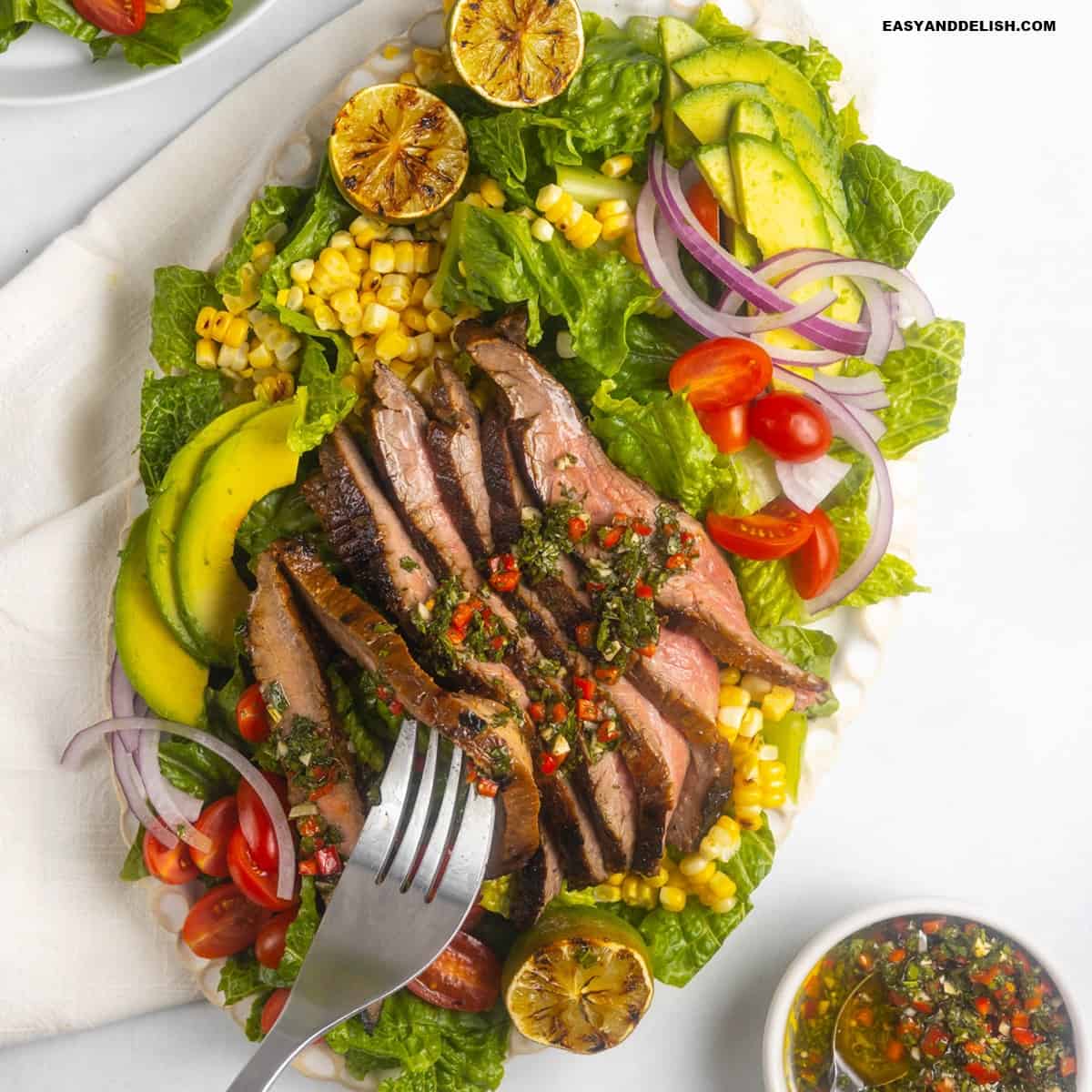 A forkful of flank steak salad taken from a platter.