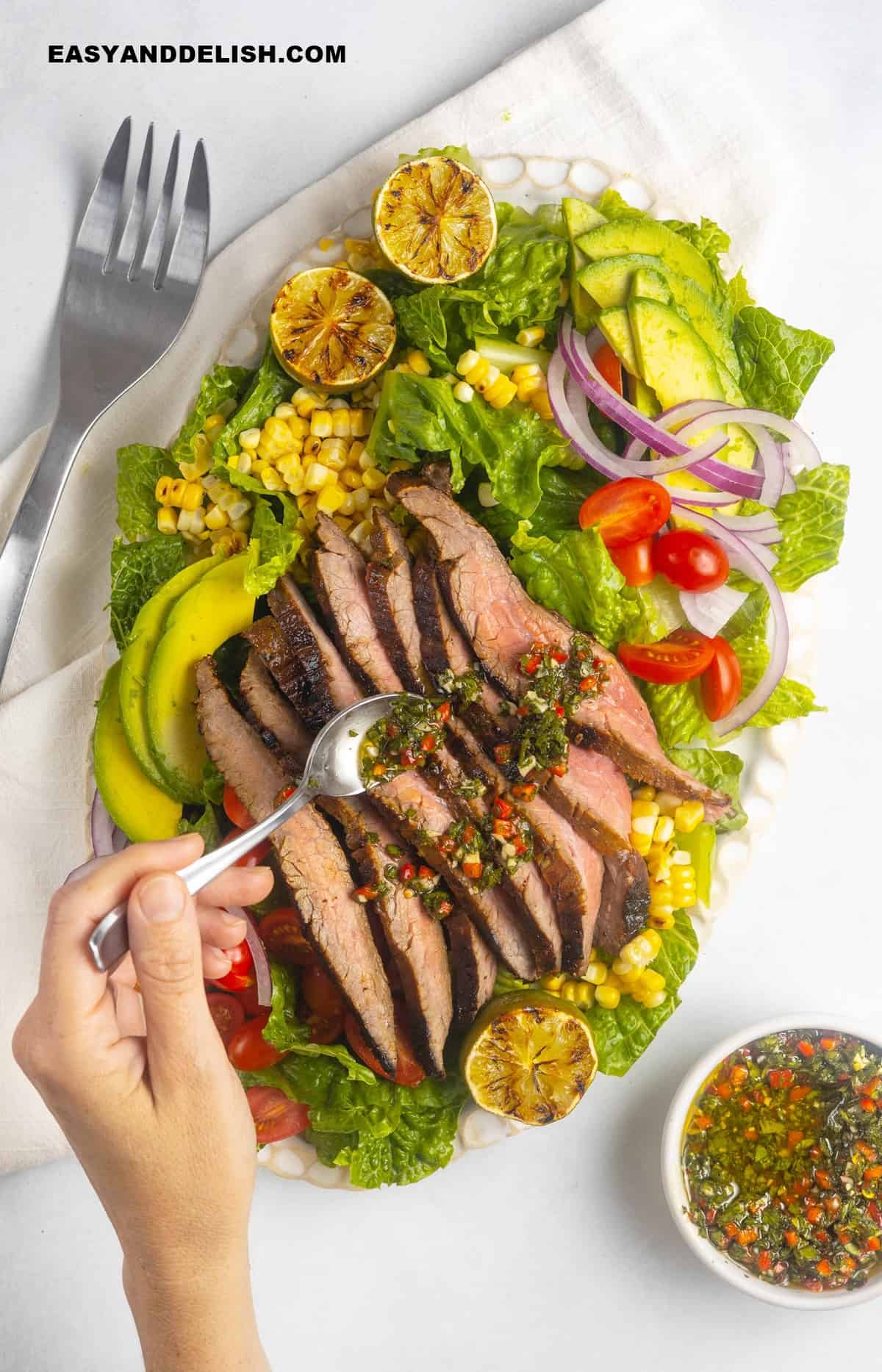 chimichurri spooned over grilled flank steak salad.