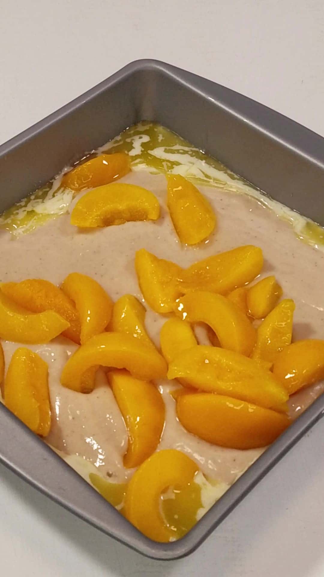 layered batter and peaches in a baking pan.