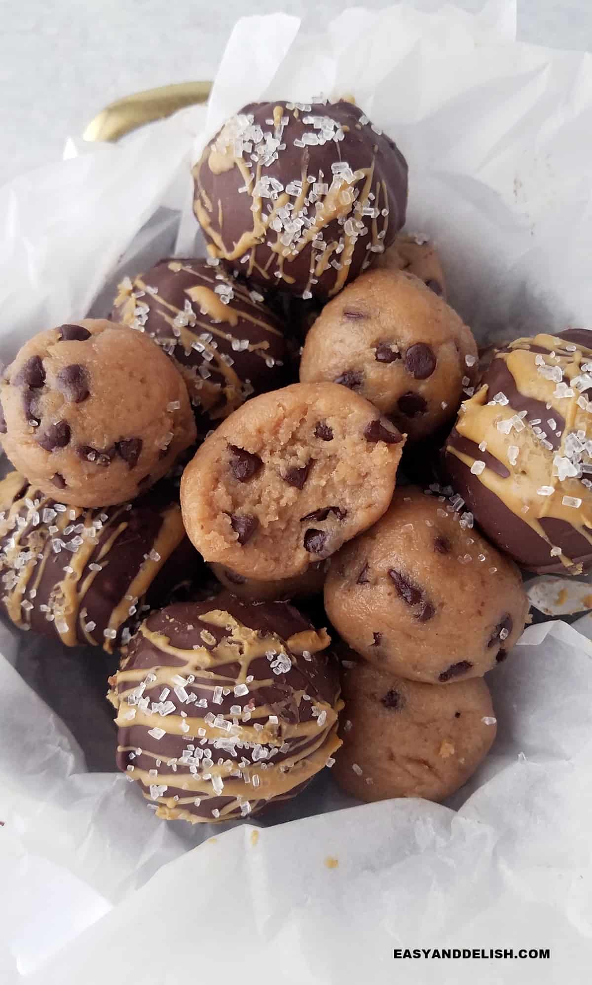 zClose up of a basket full of cookie dough protein balls, some covered in melted chocolate.