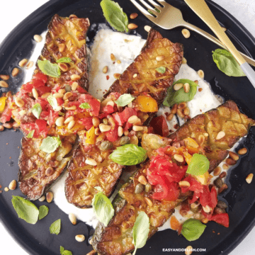 Three halves of Thomas Keller zucchini in a plate with yogurt sauce and Mediterranean topping. Plus silverware on the