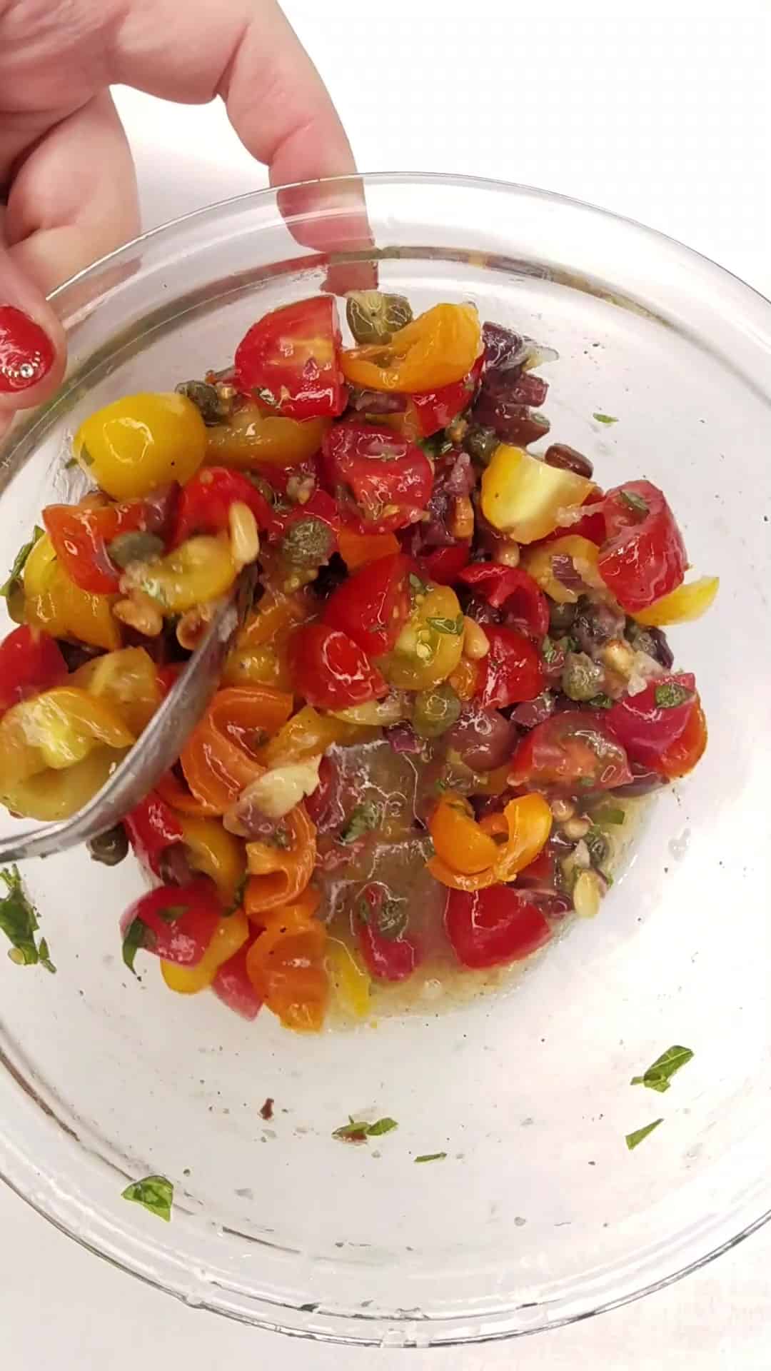 Tossing Mediterranean tossing ingredients in a bowl.