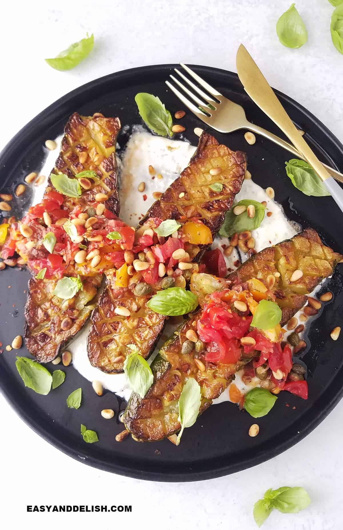 a plate with oven-baked zucchini with a yogurt sauce base and a Mediterranean topping. 