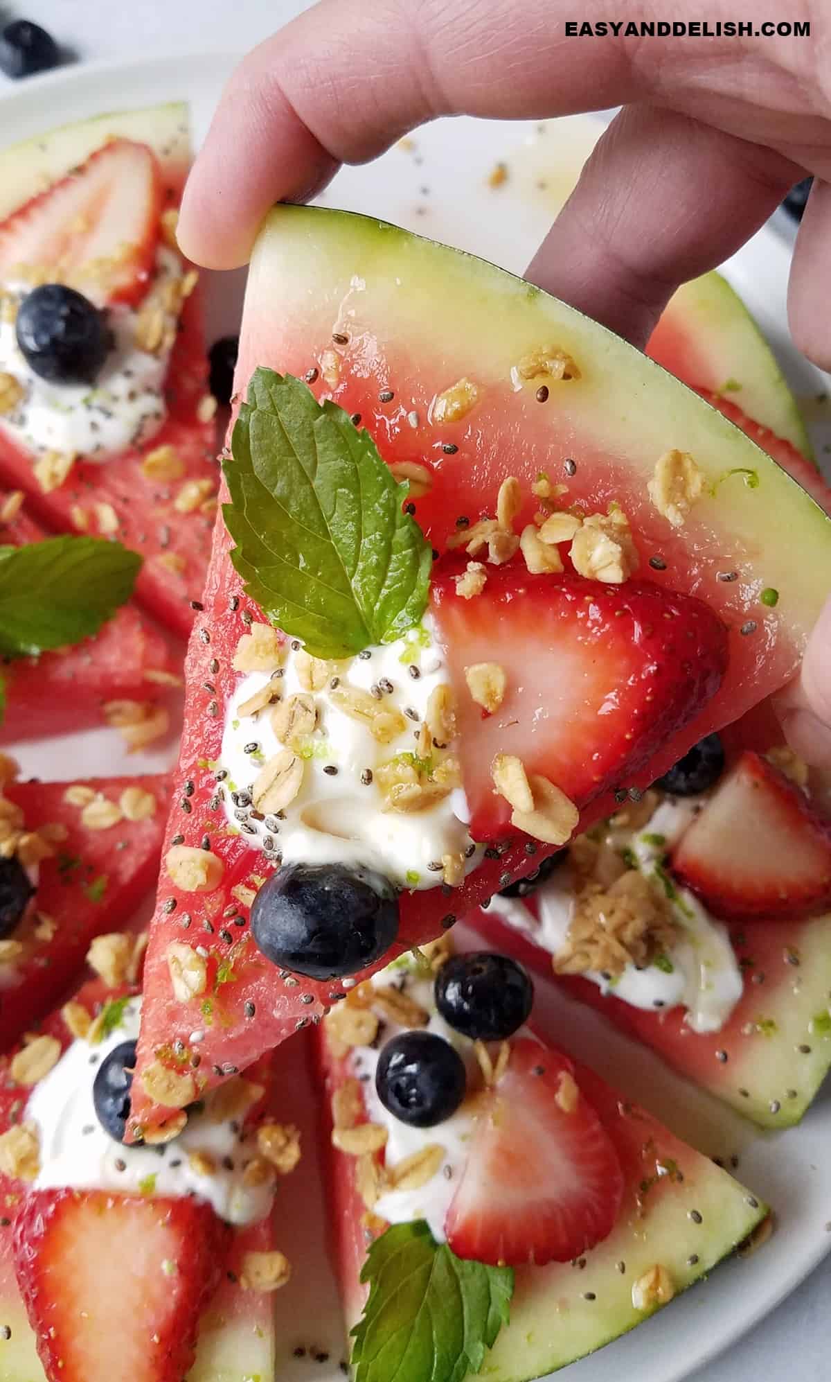 close up of a wedge of watermelon pizza for snack held up.