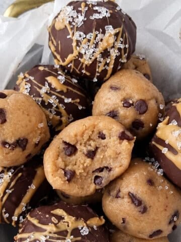 Cookie dough protein balls with chocolate chips, chocolate coating, and peanut butter drizzle.