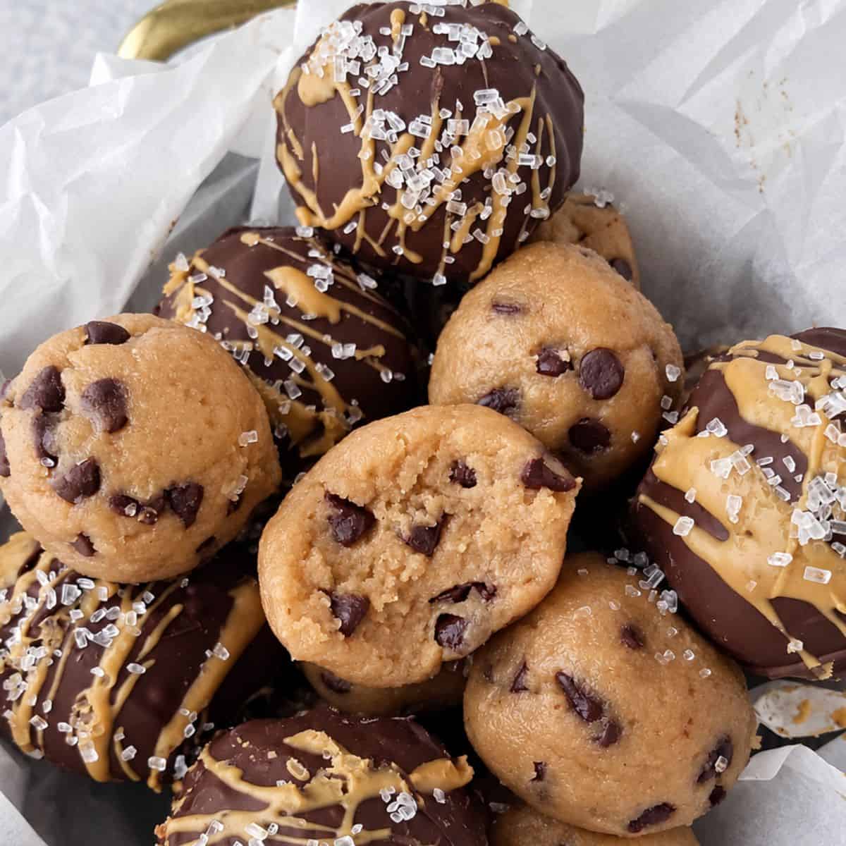 Cookie dough protein balls with chocolate chips, chocolate coating, and peanut butter drizzle.