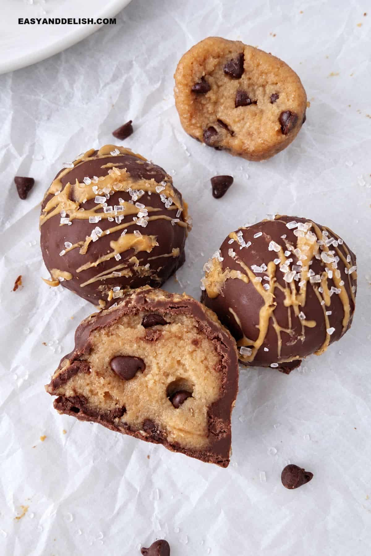 Chocolate-coated protein balls cut open on parchment paper.