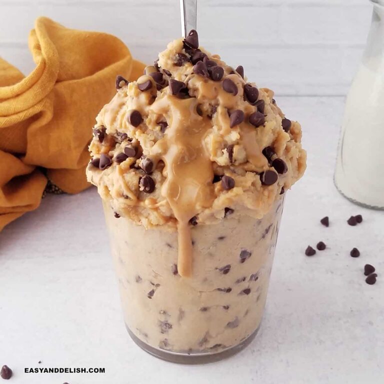 a glass with protein cookie dough with chocolate chips and a drizzle of peanut butter.