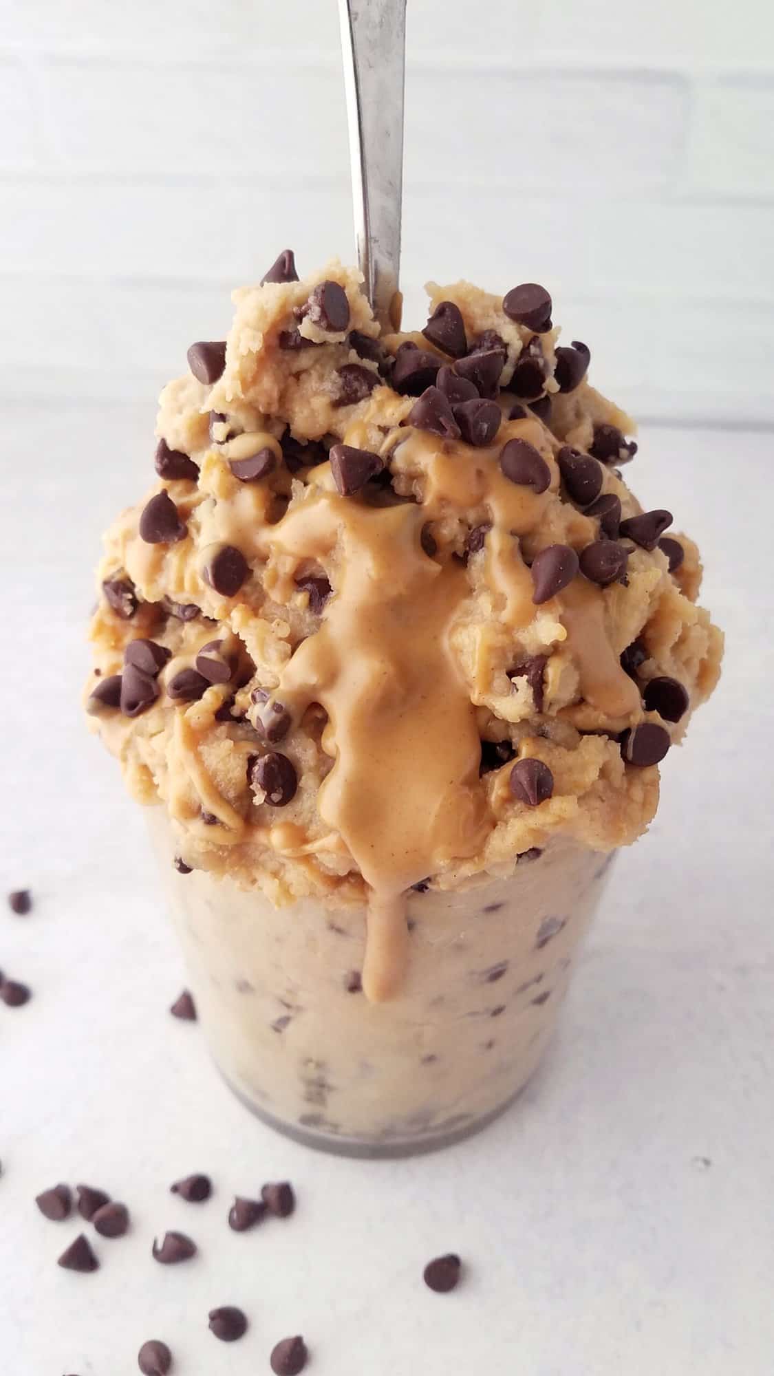 chocolate chip edible cookie dough with peanut butter drizzle in a glass.