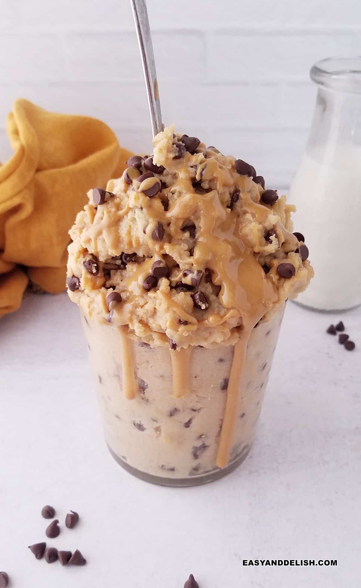 a bottle of milk behind a glass of high protein cookie dough.
