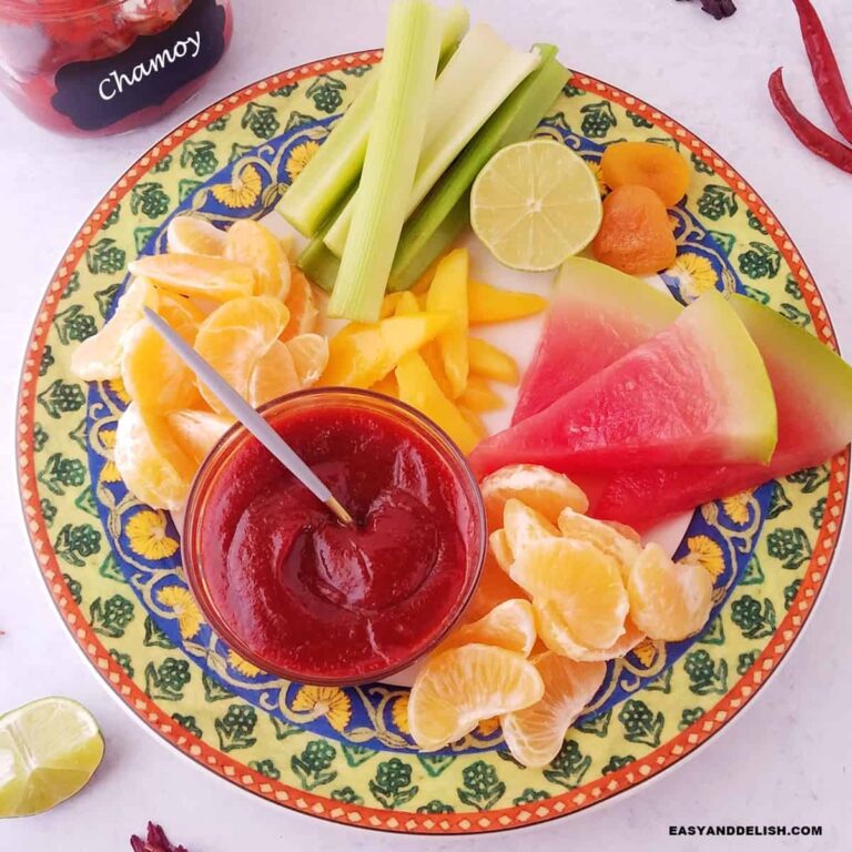 a bowl with homemade chamoy sauce served ina platter with assoreted fruits.