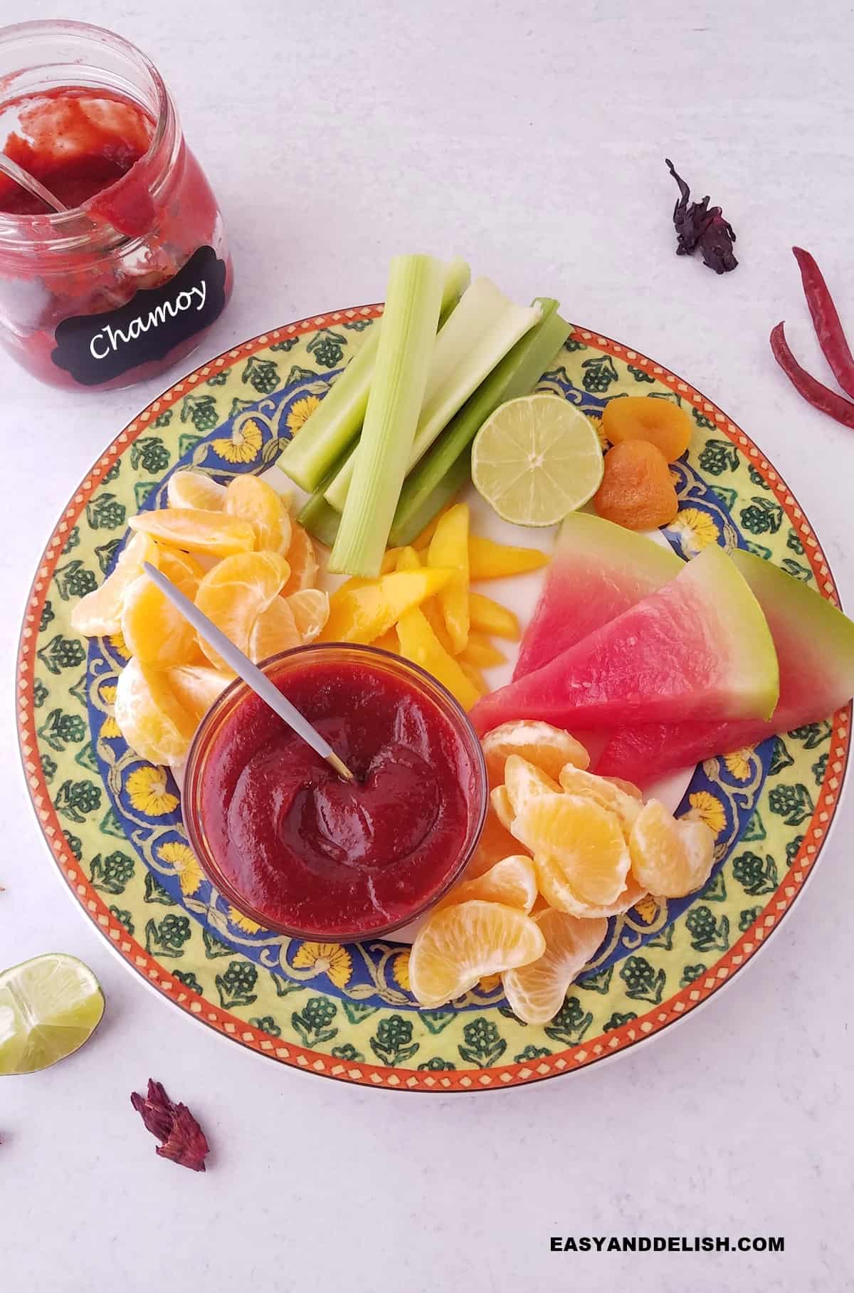 a plate with fruits, veggies, and chamoy sauce.