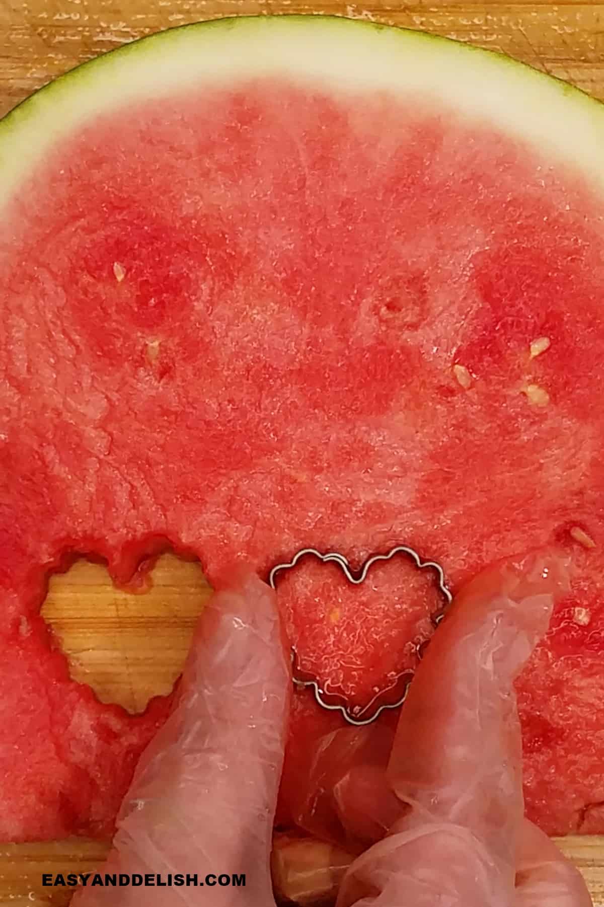 cookie cutter in teh shape of a heart cutting melon into shapes.