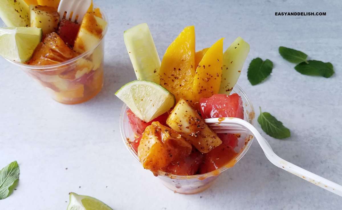 fruits cups on a table with fresh garnishes around them.