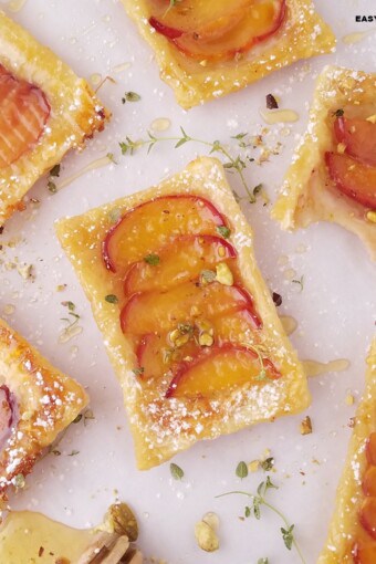 peach puff pastry tarts dusted with powdered sugar and garnished with crushed pistachios.