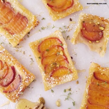 peach puff pastry tarts dusted with powdered sugar and garnished with crushed pistachios.