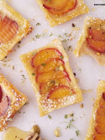 peach puff pastry tarts dusted with powdered sugar and garnished with crushed pistachios.