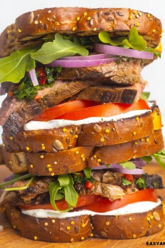 A pile of steak sandwich on a cutting board.