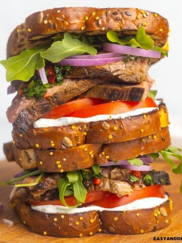 A pile of steak sandwich on a cutting board.