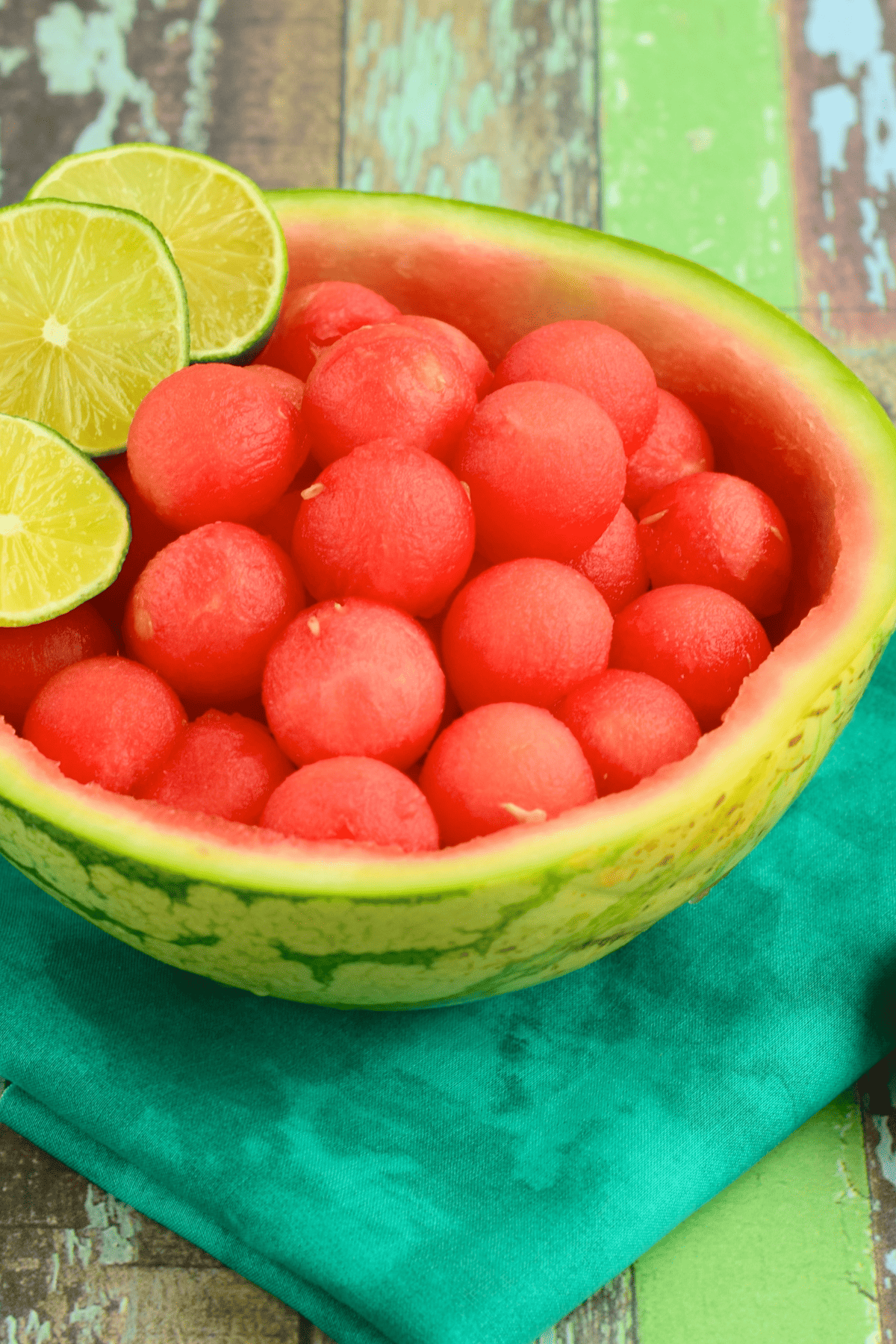 a melon bowl full of melon balls with limes slices garnishing the top.