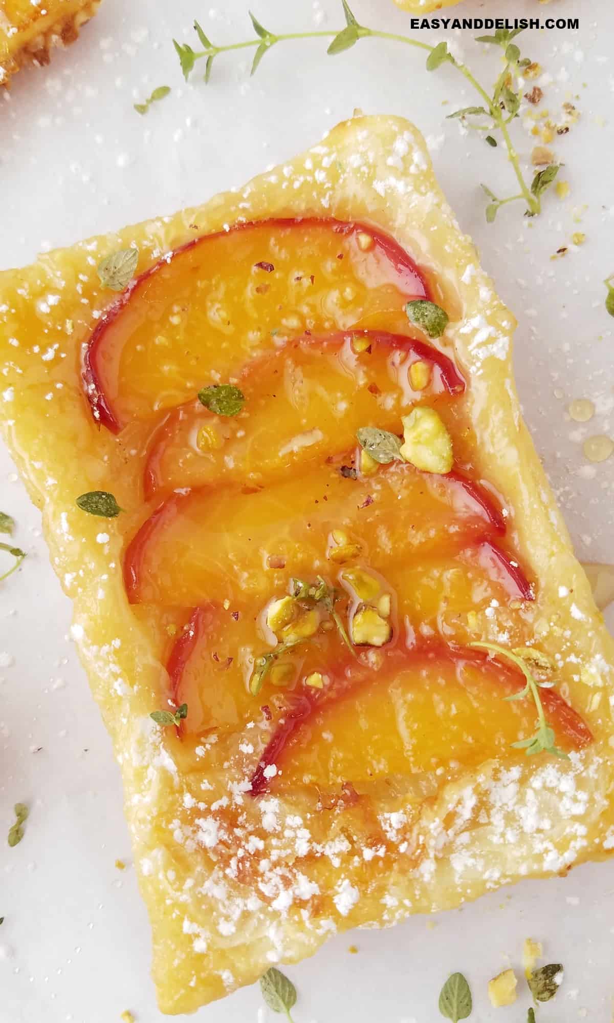 individual peach tart with puff pastry  topped with pistachios.