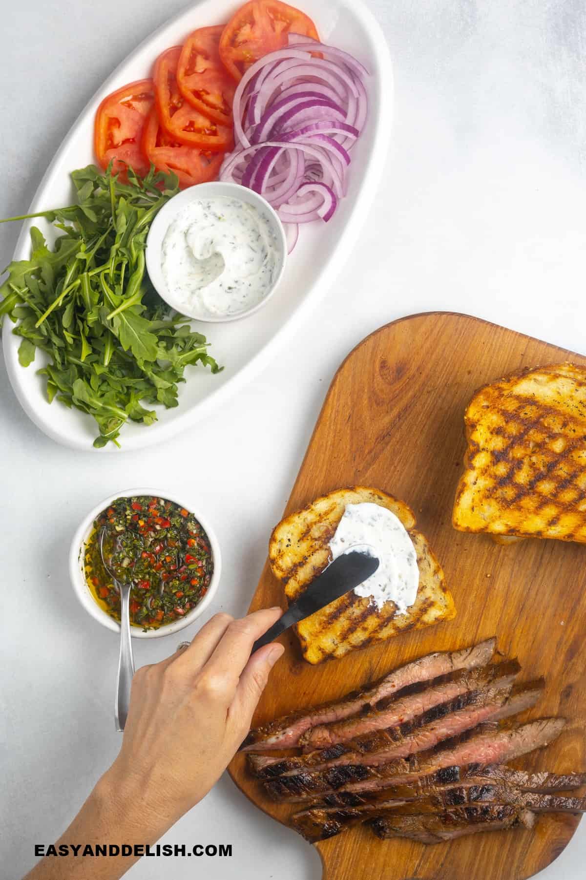 Smearing the yogurt spread on top of the bread with otehr ingredients around it.