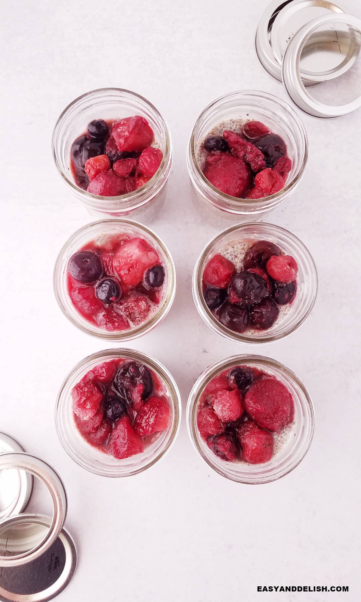 basic chia pudding with berries in mason jars with lids on the side.