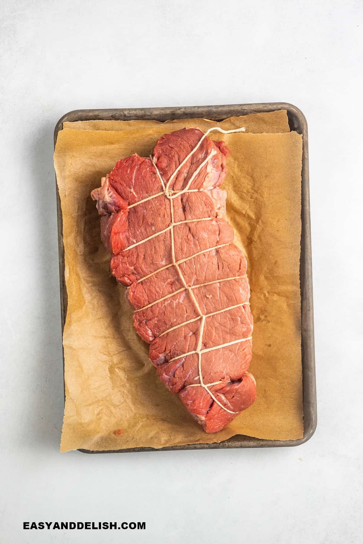 meat tied with kitchen sstrings in a roasting pan.