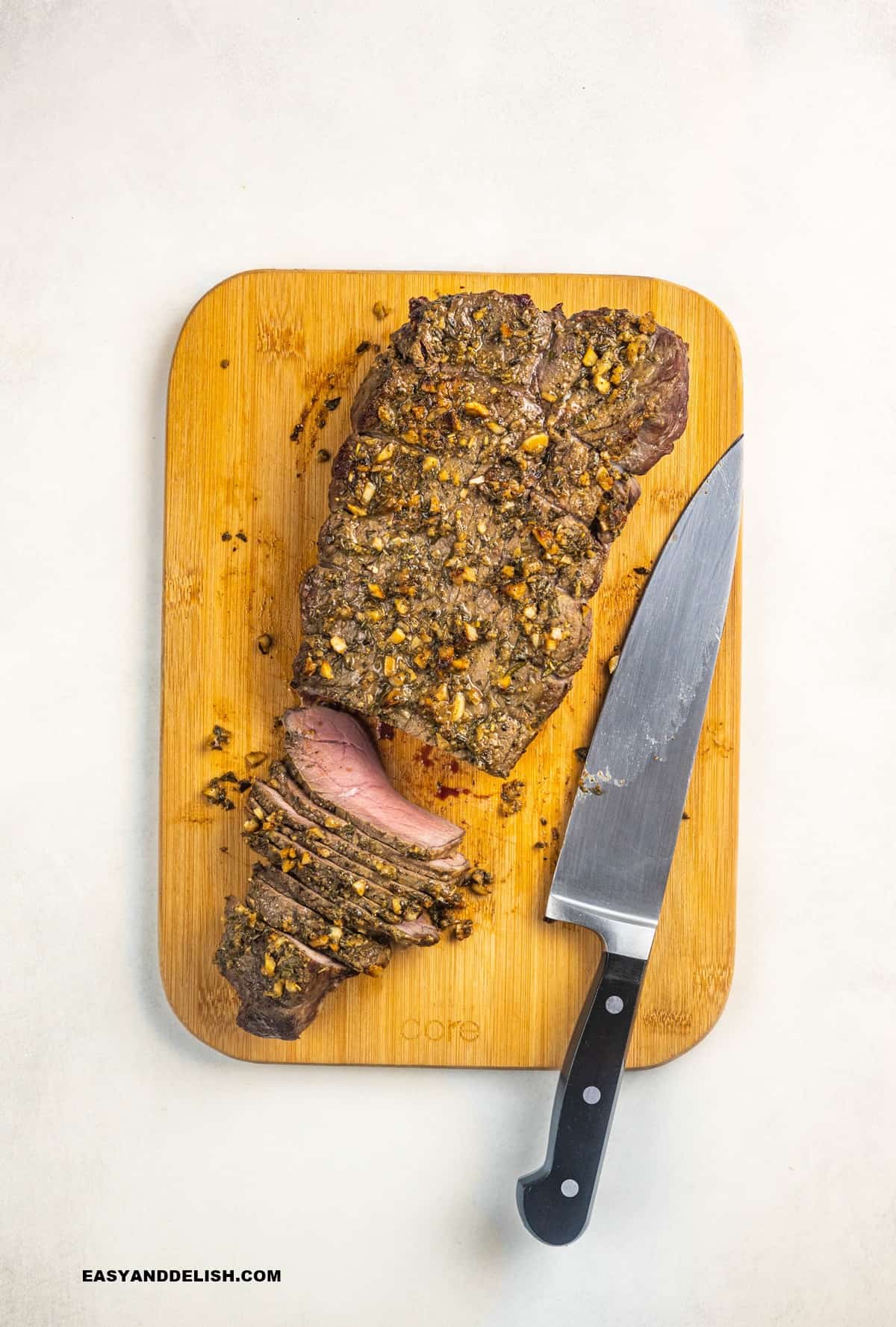 sliced beef roast on a cutting board with a knife on the side. 