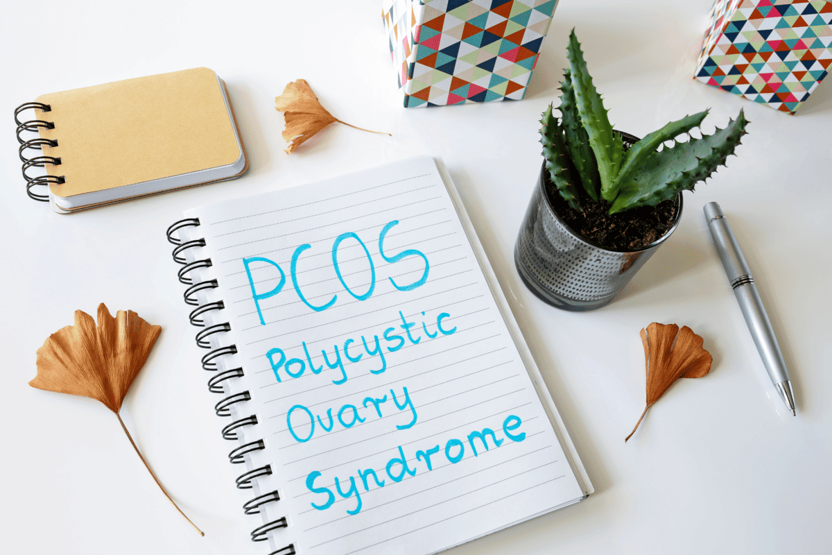 a notebook with the word PCOS and a few things around it.