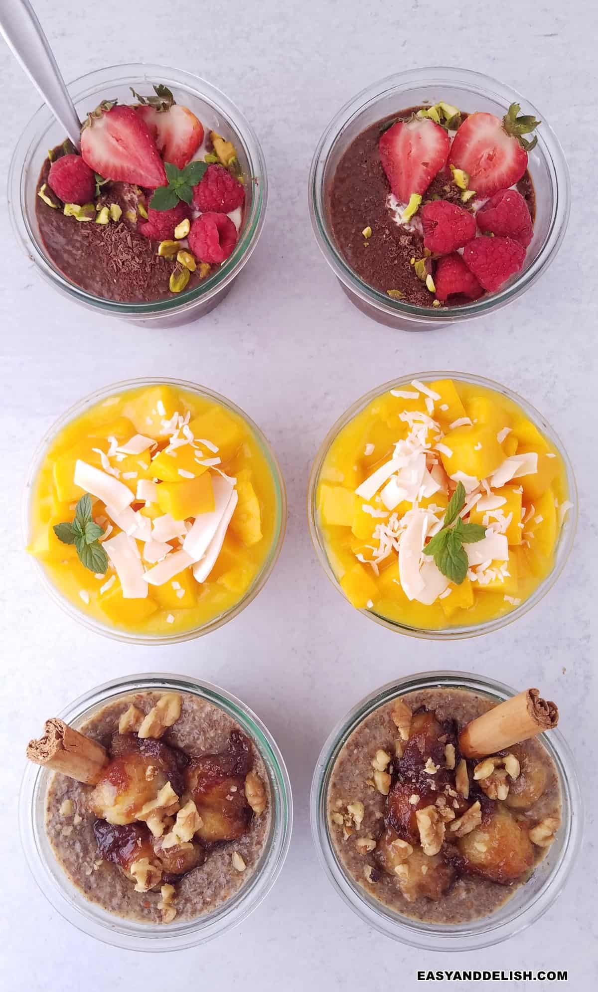 6 jars with 3 flavors of chia pudding: chocolate, coconut with mango, and banana on a table.