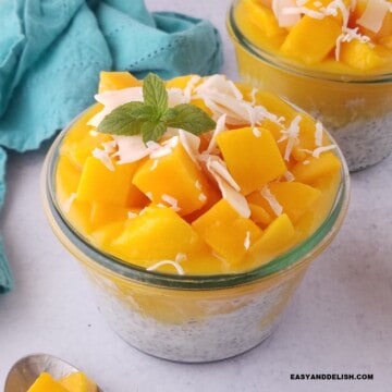 close up of a jar of coconut chia pudding with mango chunks and coconut flakes.