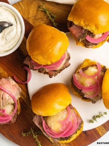 a bunch of roast beef sliders with aioli and herbs on the side.