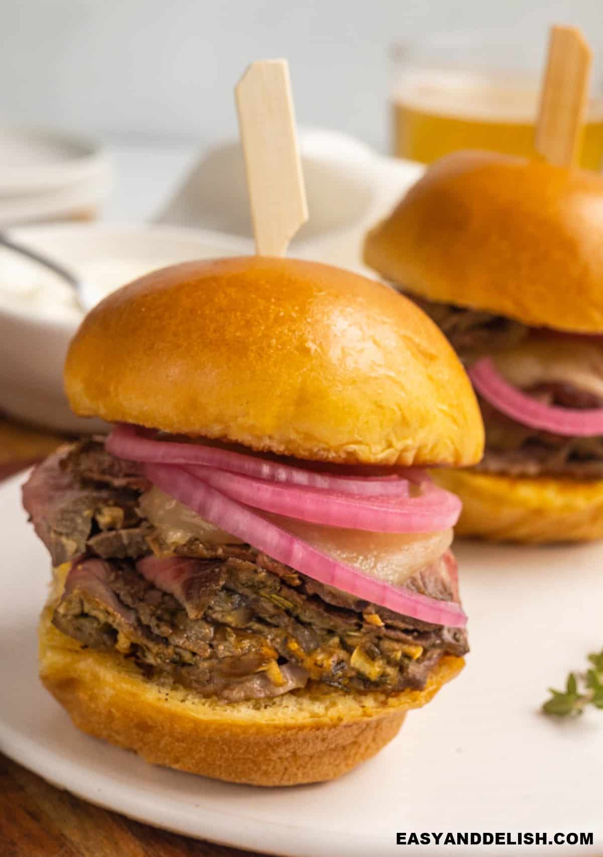 one roast beef slider on a tray with some others on the background. 