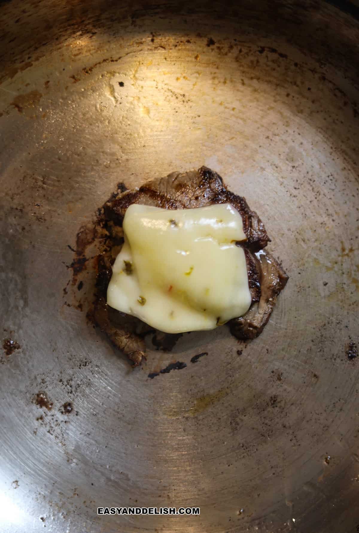 roast beef slices topped with cheese heated on a skillet. 