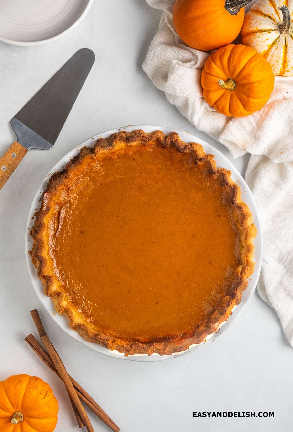 Baked sugar-free pumpkin pie with ingredients around it.