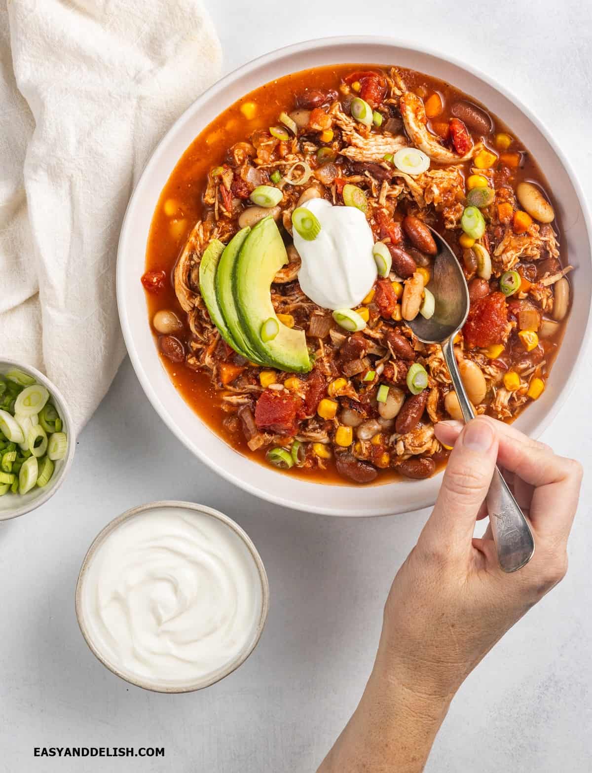 A hand spooning soup ina bowl.  