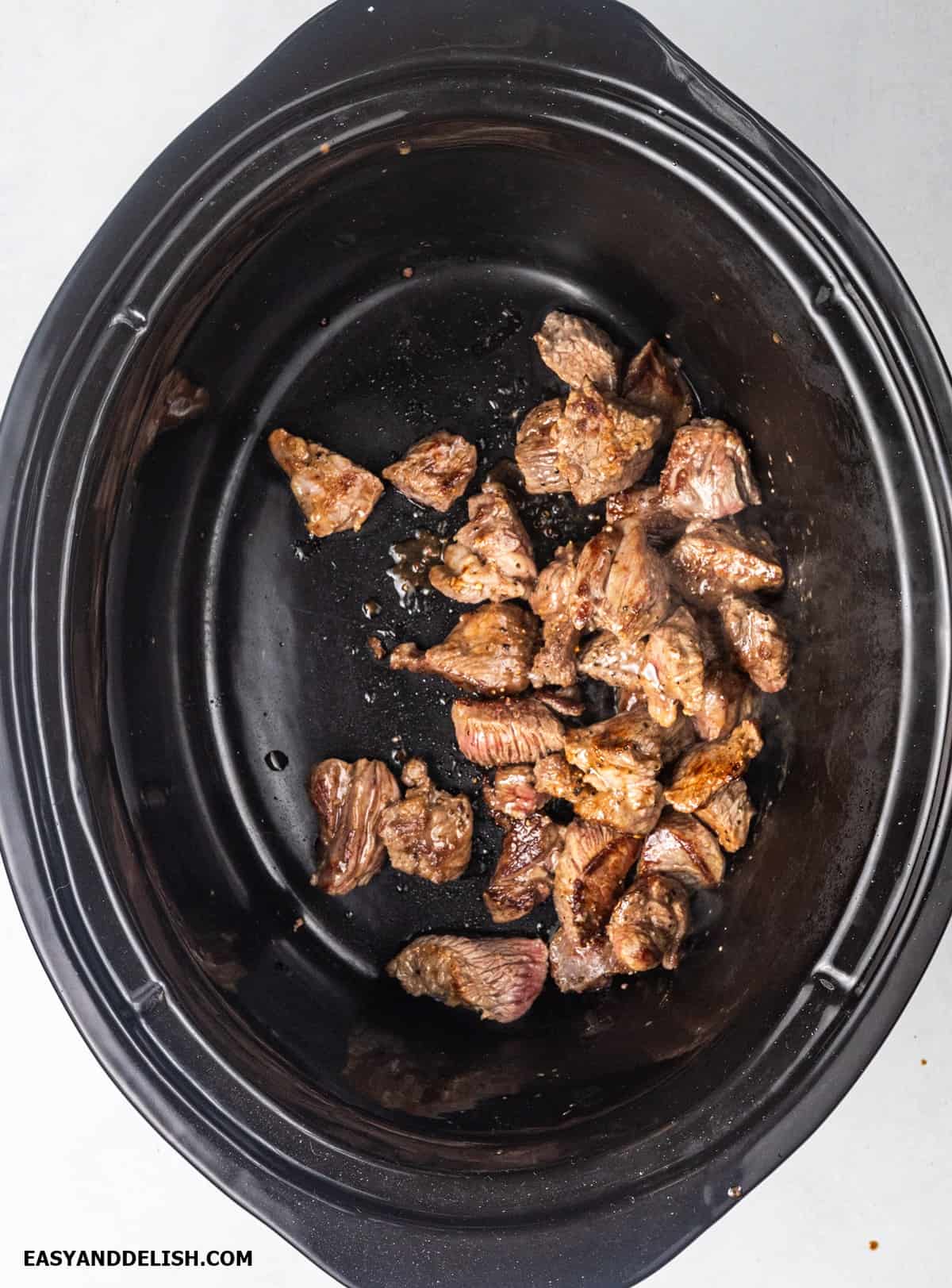 Browned beef chunks in a crockpot.