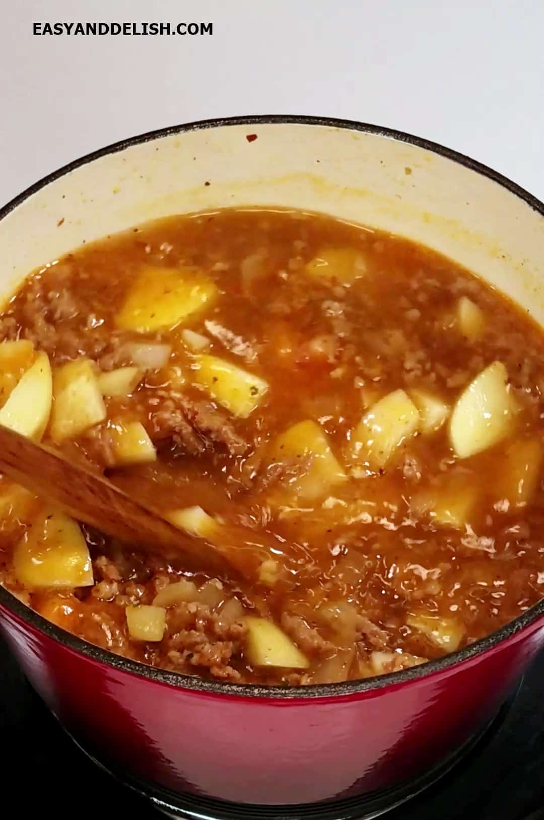 Potatoes and broth added to a pot of boiling soup. 