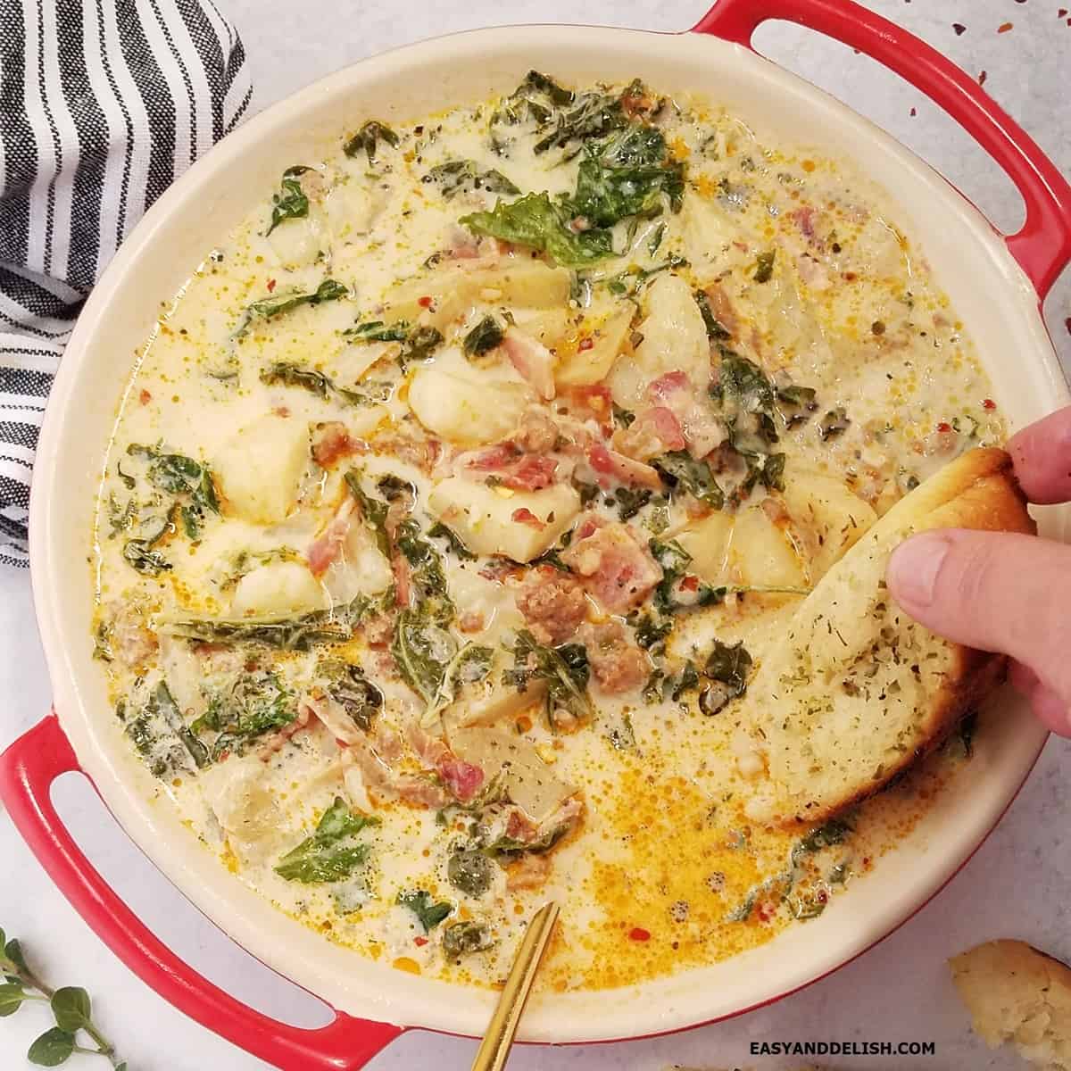 A piece of toast dipped in a bowl of Olive Garden Zuppa Toscana Soup.