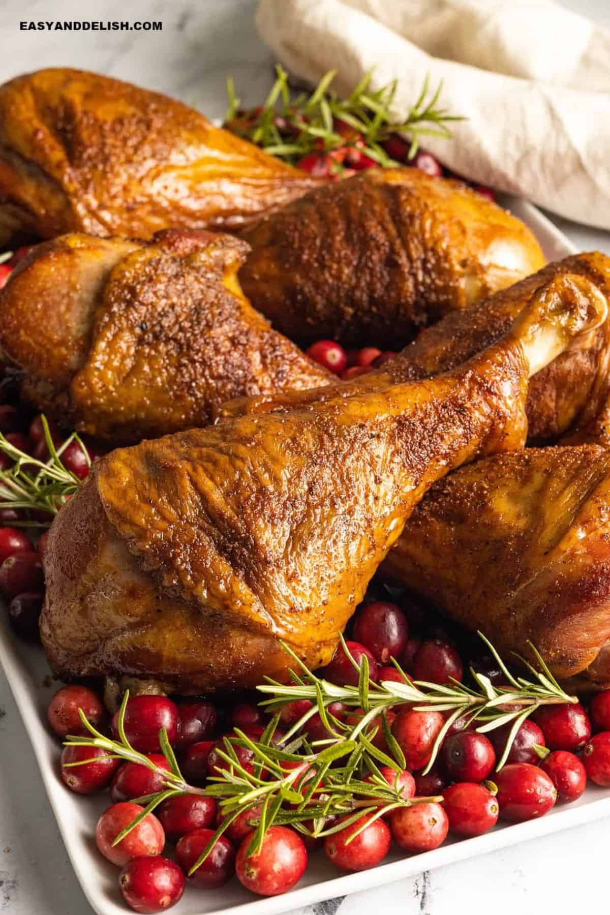 Roasted turkey legs arranged with fresh cranberries and rosemary.