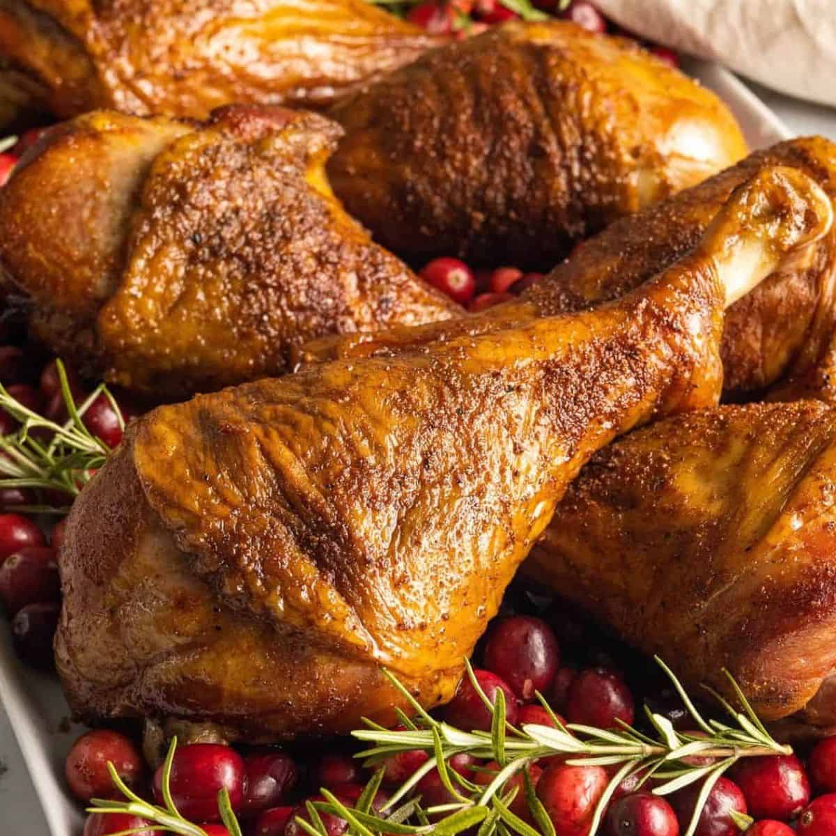 Smoked turkey drumsticks garnished with fresh cranberries and rosemary.