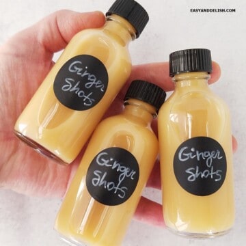 Three bottles of ginger shots held flat.