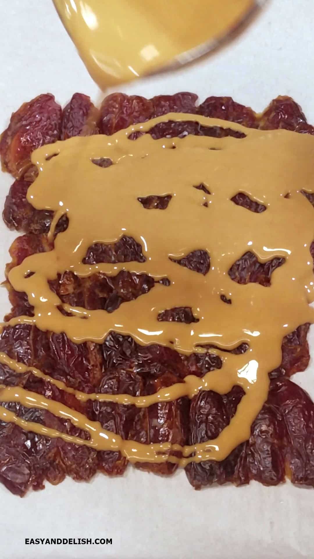 Melted peanut butter poured on top of a layer of dried fruits.