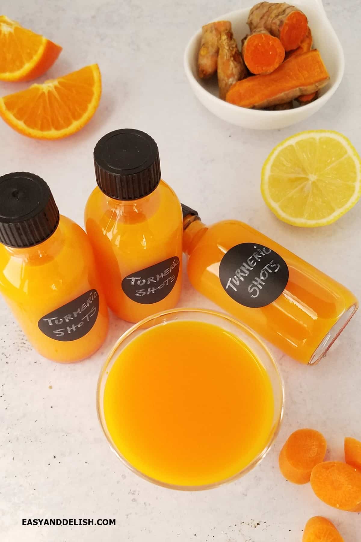 Several ingredients of the recipe near turmeric shots in bottles and a glass.  